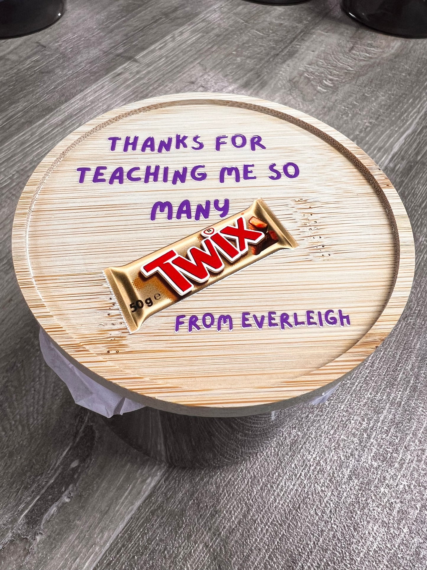 Wooden coaster with a chocolate bar design and text on a gray surface
