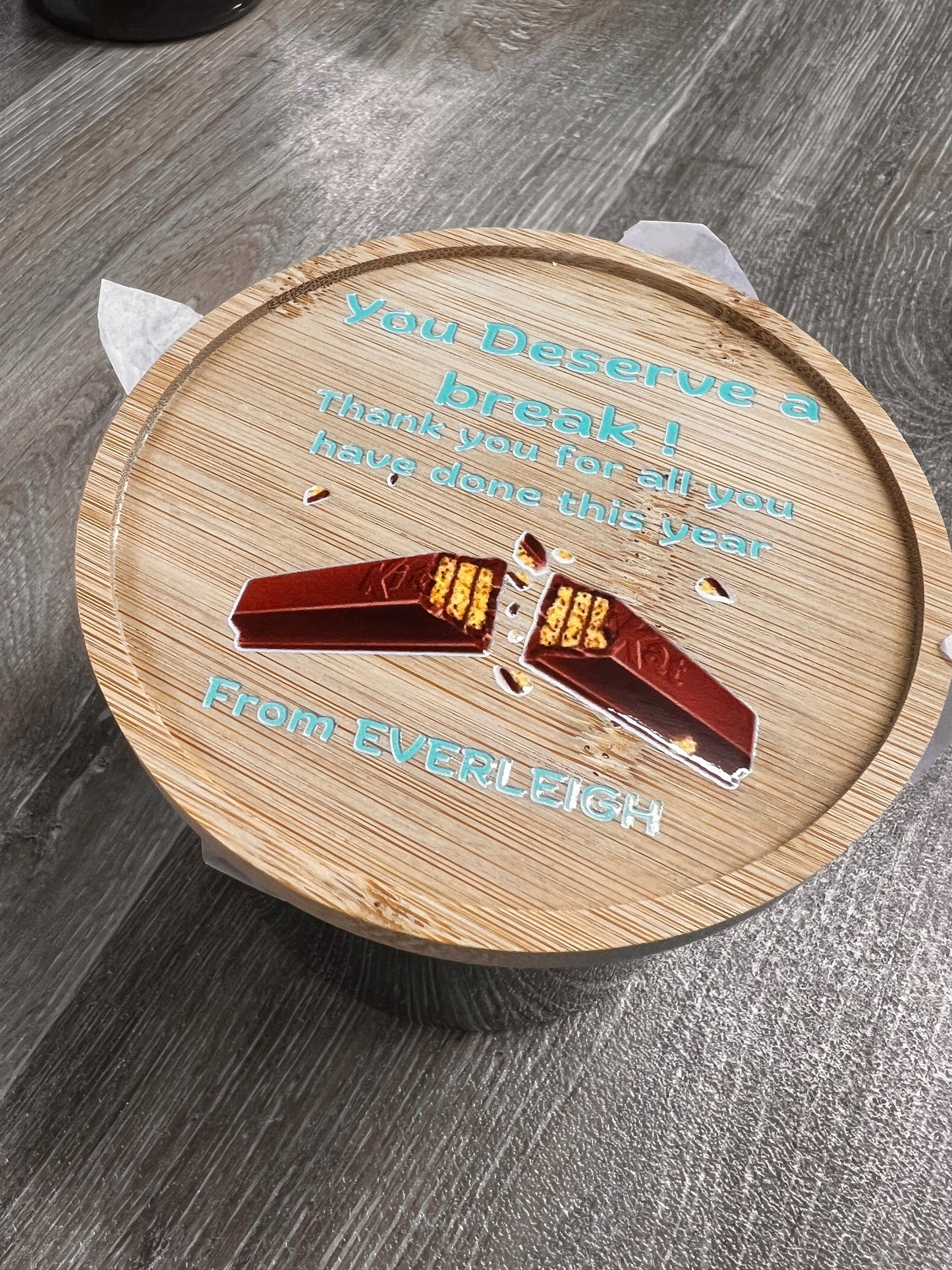 Wooden coaster with a design and text on a wooden surface
