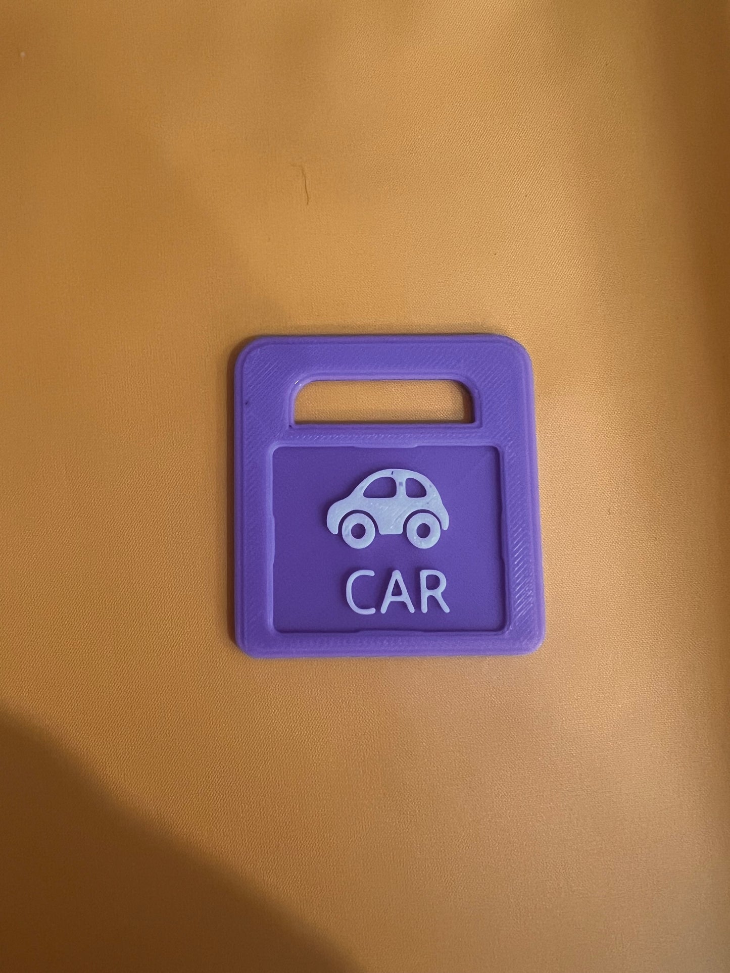Purple anxiety support tag car key cover with a car icon on a brown background